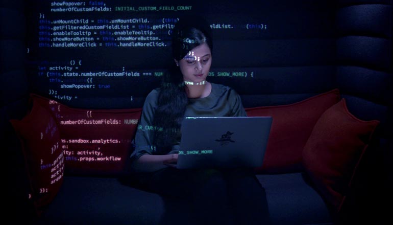 A woman sitting in front of her laptop writing codes