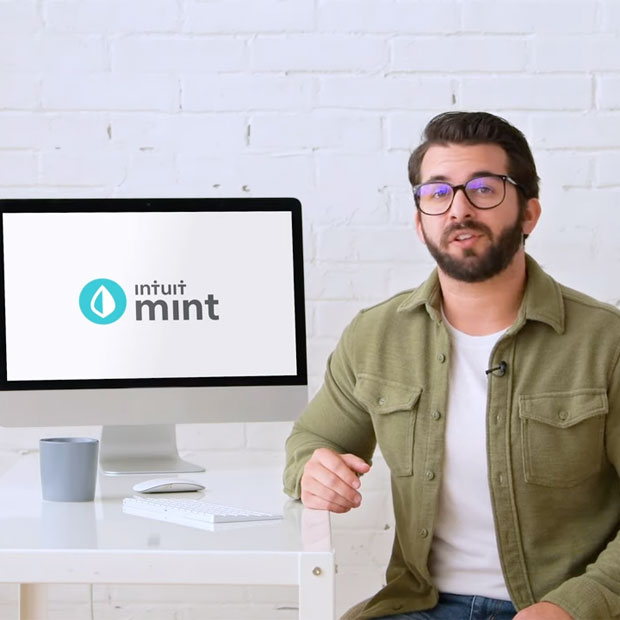 A person sitting next to a monitor that's showing the Mint logo